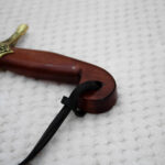 Close-up of the SiCh-Souvenir saber hilt, showing the curved reddish-brown grip and decorated guard