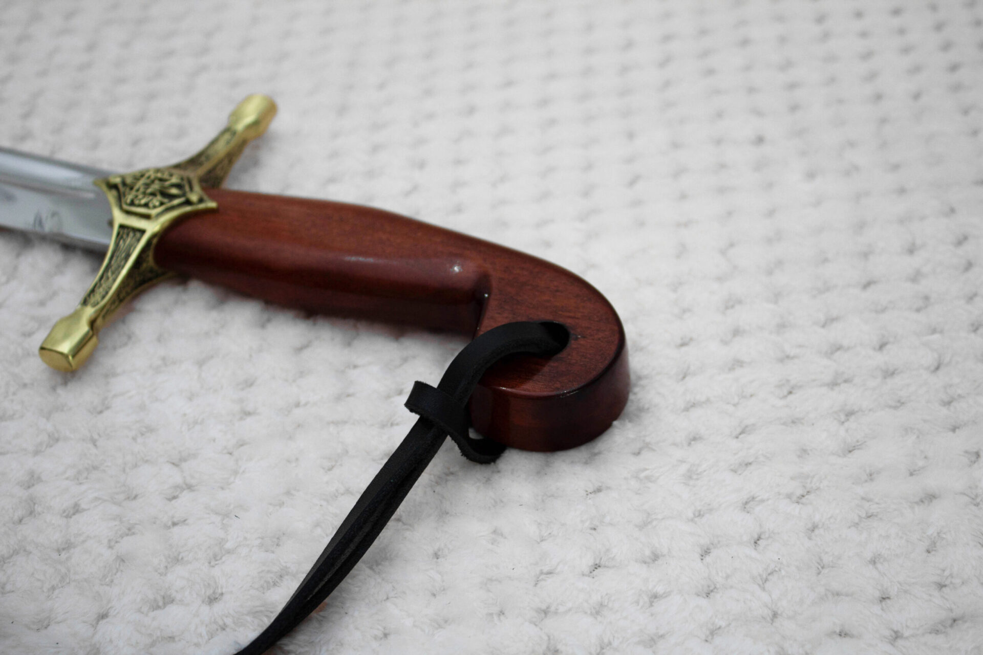 Close-up of the SiCh-Souvenir saber hilt, showing the curved reddish-brown grip and decorated guard