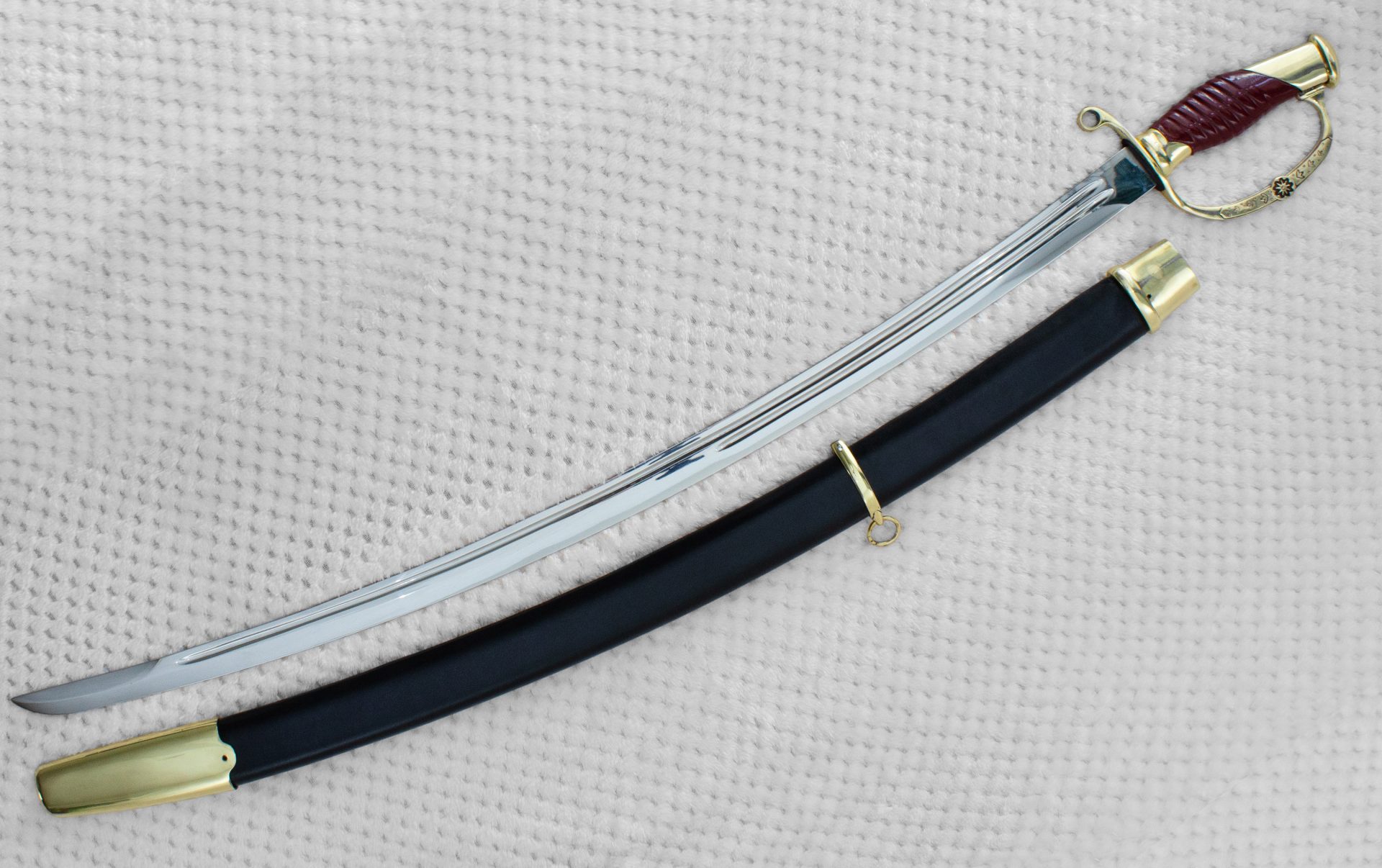 Dragoon saber with exposed blade beside its black scabbard, viewed at an angle