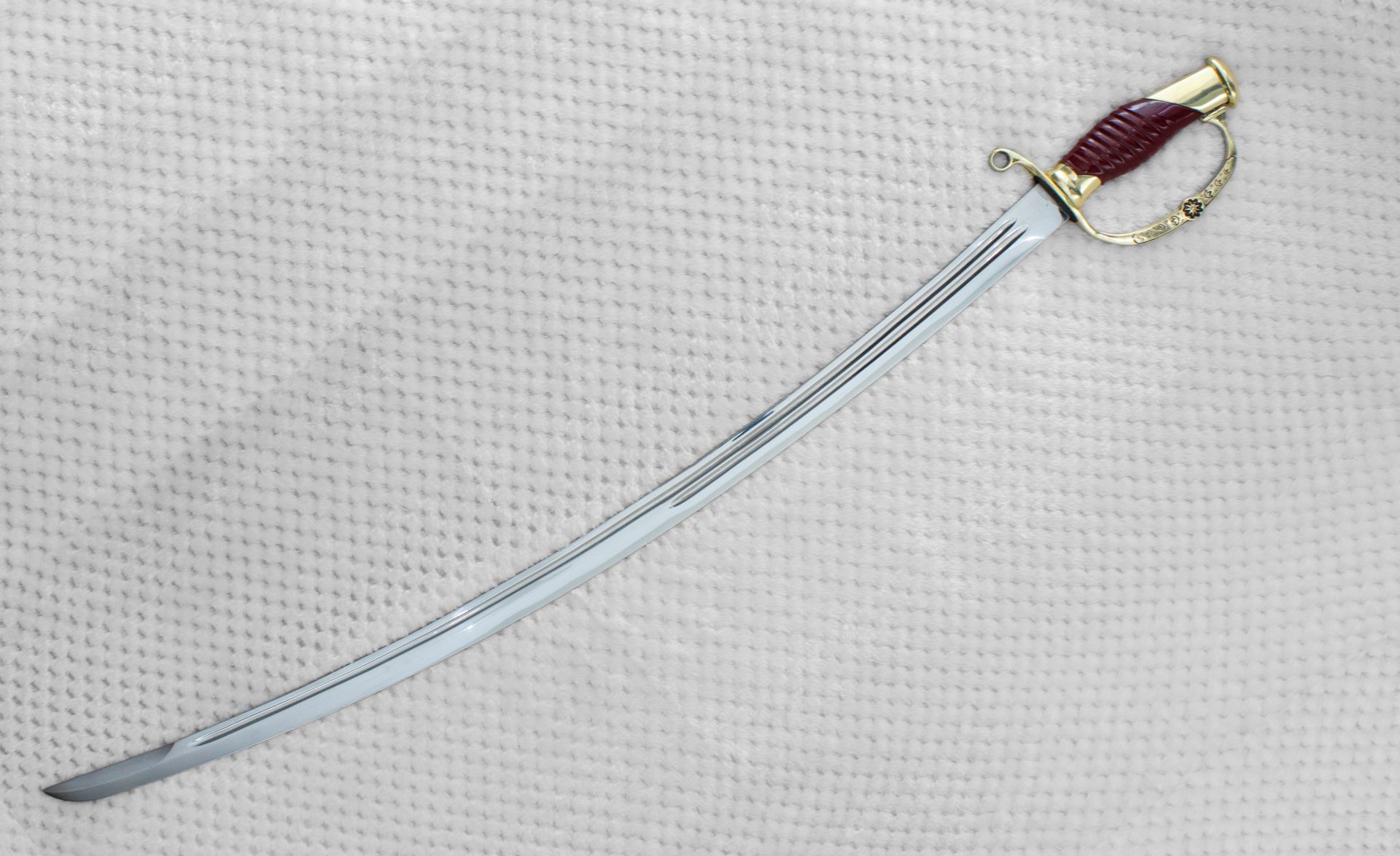 Curved Dragoon saber blade with a long fuller and knuckle guard, viewed at an angle
