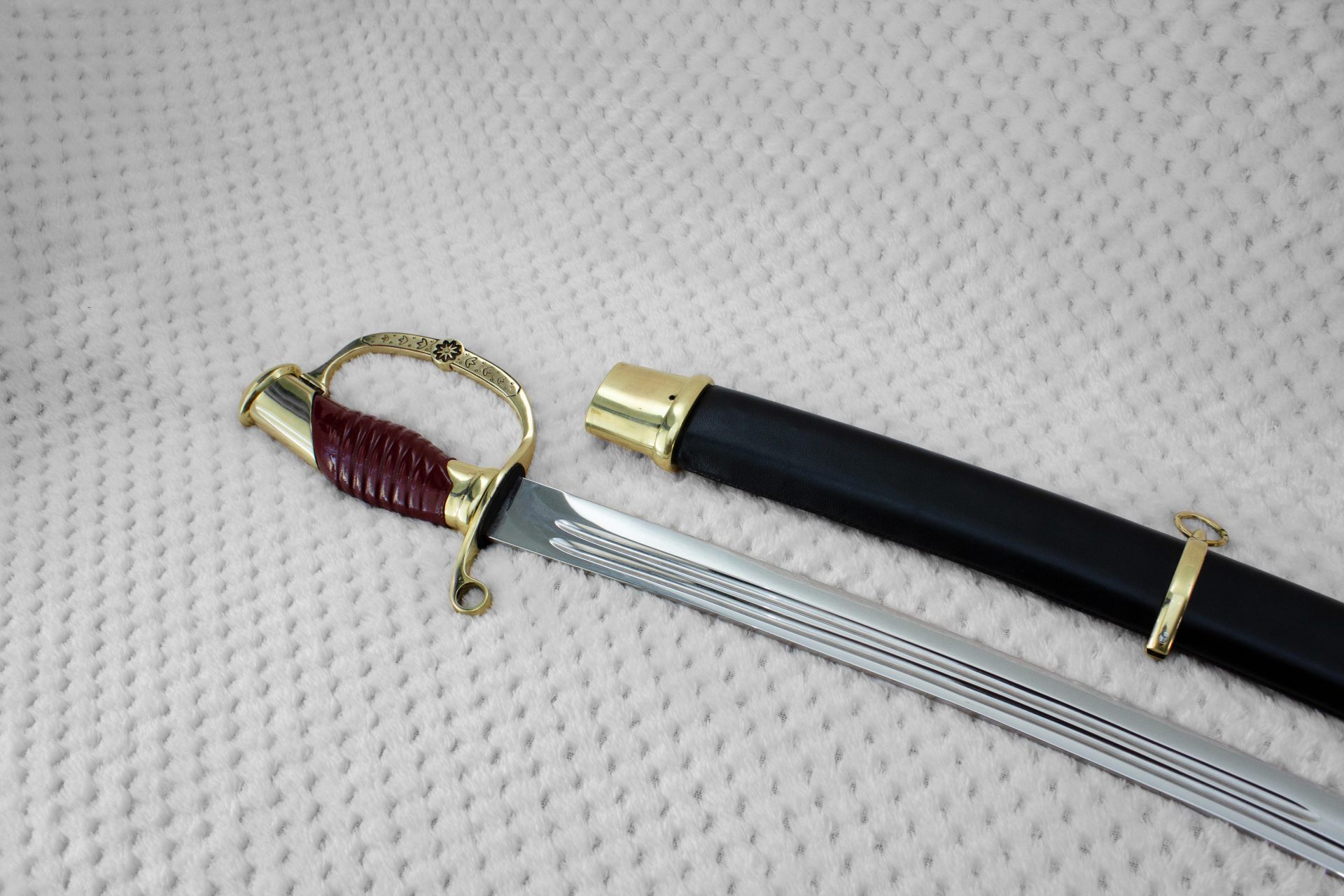 Dragoon saber with a red-brown grip and curved knuckle guard beside its black scabbard