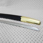 Close-up of the Dragoon saber blade tip beside the smooth metal tip of its black scabbard