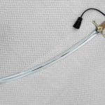 Curved SiCh-K saber blade with a long fuller and brown grip, viewed at an angle