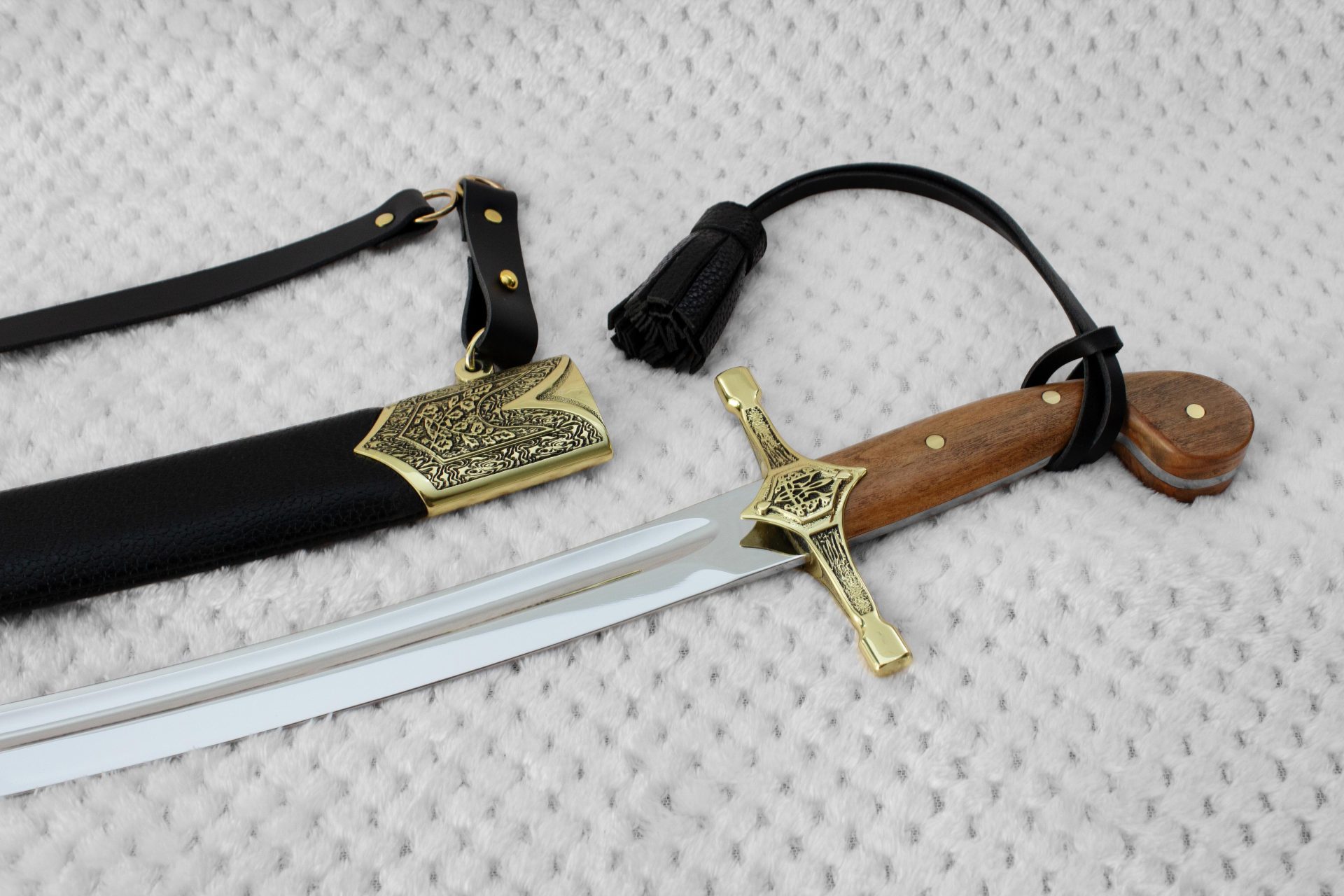 SiCh-K saber beside its black scabbard, showing the brown grip, decorated guard and tassel