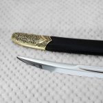 Close-up of the SiCh-K blade tip beside the decorated tip of its black scabbard