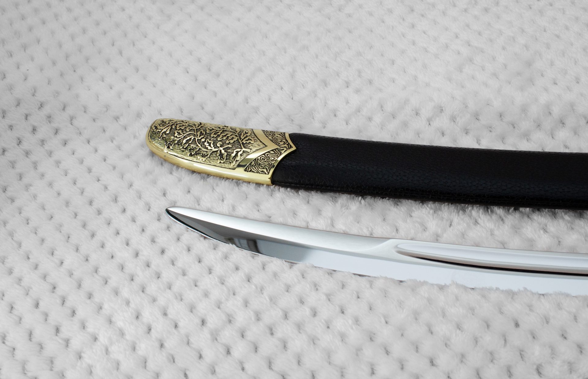 Close-up of the SiCh-K blade tip beside the decorated tip of its black scabbard
